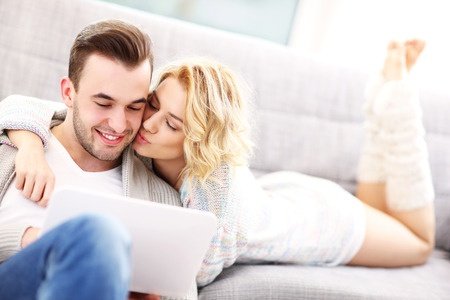 a picture of a romantic couple with laptop in living room