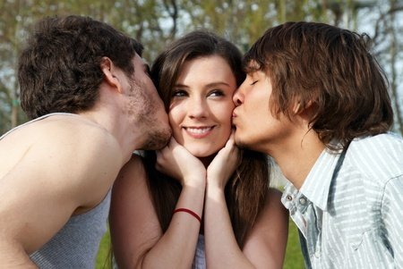 happy girl kissed by two young boys
